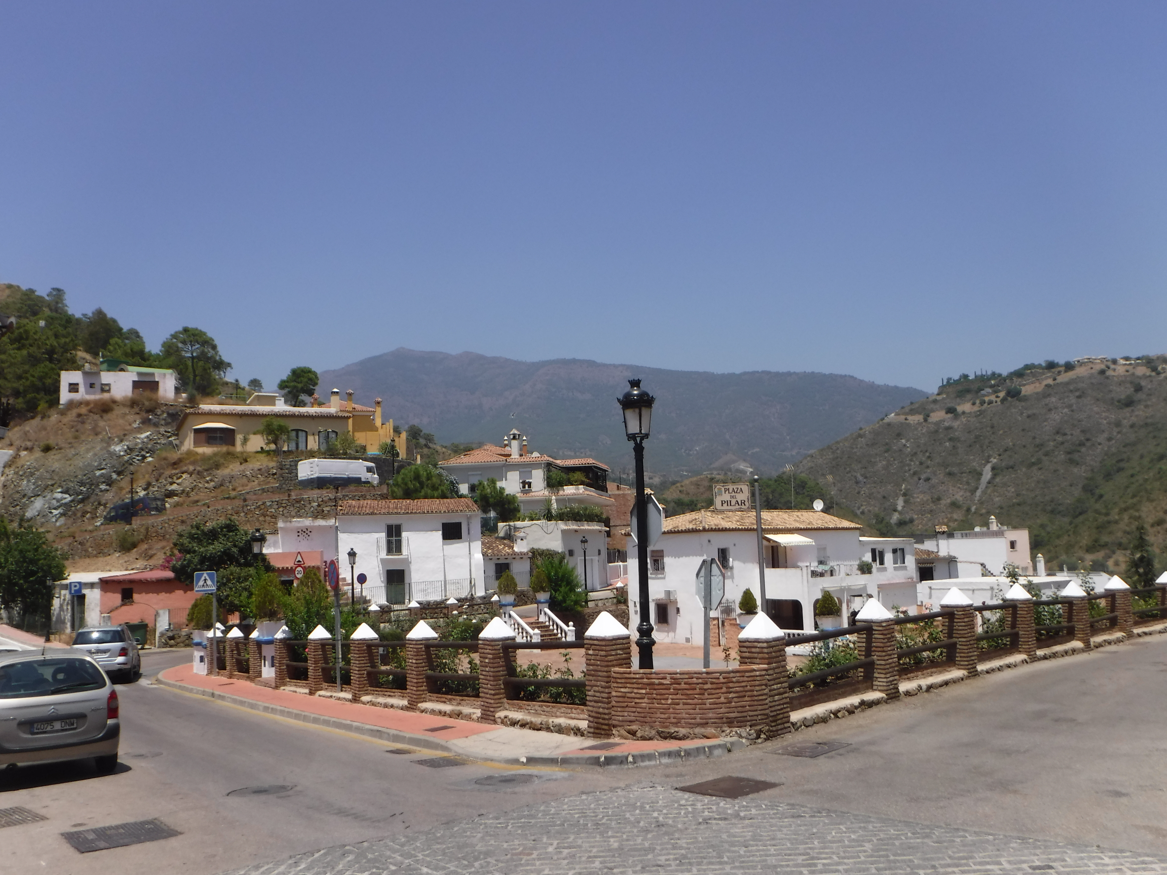 Street scene in Benahavís, Spain, with white houses and mountains in background.